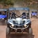 3 off road buggies, each with a driver and a passenger, traveling on a dirt path